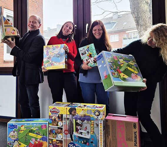 Vier lachende Mitarbeiter:innen halten jeweils ein Spiel in der Hand